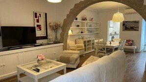 Ein modernes Wohnzimmer mit einer Couch, einem Couchtisch, einem Fernseher und einem Essbereich mit Stühlen und einem Tisch.