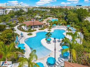 A resort with a large central pool, multiple smaller pools, and a surrounding lounge area with umbrellas. - The Epic 7 Vista Cay Resort Orlando Florida (Orlando)