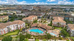 Zona residencial con edificios de apartamentos, una piscina central y un patio ajardinado.