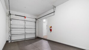 Siisti, tyhjä käytävä, jossa on kiinni oleva autotallin ovi ja seinälle asennettu palosammutin.