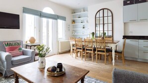 Una sala de estar moderna con comedor, cocina y un gran ventanal con cortinas.