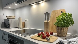 A modern kitchen with a built-in oven, a microwave, and a cutting board with tomatoes. - Ferienwohnung mit Weitläufigen, Parkähnlichen Garten, Pavillon und Bouleplatz (Bosau)