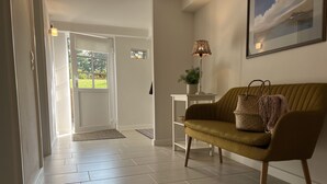 A modern interior with a sofa, a lamp, and a door leading to a garden. - Ferienwohnung mit Weitläufigen, Parkähnlichen Garten, Pavillon und Bouleplatz (Bosau)