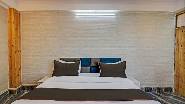 A bedroom with a bed, wooden walls, and a ceiling light. - Umen Hotel Sector 66 (Noida)