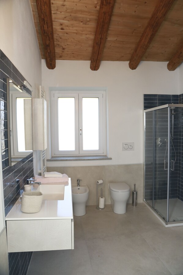 Un baño moderno con ducha, inodoro, bidé y lavamanos con espejo.