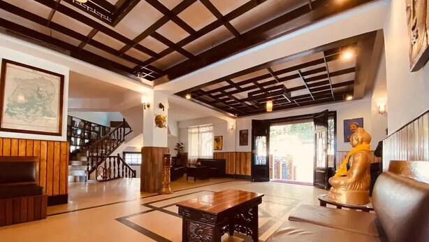 A spacious lobby with a wooden bench, a coffee table, and a statue. - Dew Pond (Gangtok)