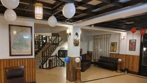 A lobby with a wooden bench, a staircase, and a map on the wall. - Dew Pond (Gangtok)