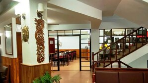 A spacious lobby with a staircase, wooden decor, and a dining area in the background. - Dew Pond (Gangtok)