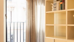 Ein Zimmer mit Fenster, Vorhang und einem Bücherregal voller Bücher.