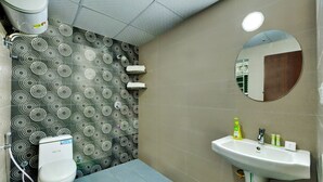 A bathroom with a toilet, sink, and mirror. - Yahweh Suites (Bengaluru)