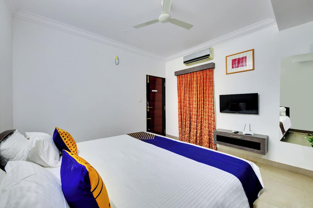 Een hotelkamer met een bed, een plafondventilator, een airconditioning, een televisie en een spiegel.