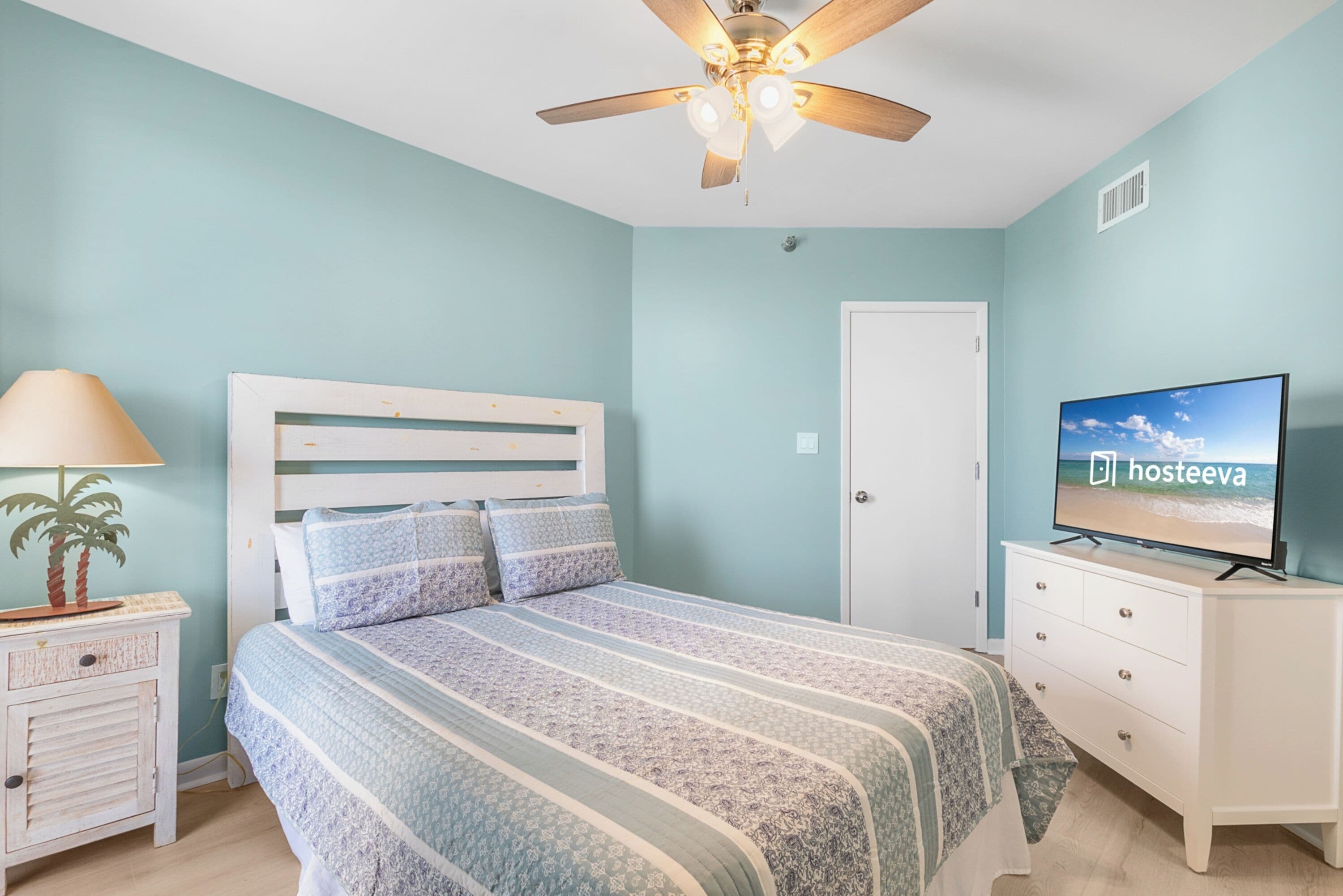 A bedroom with a bed, a TV, a ceiling fan, a nightstand, and a dresser.