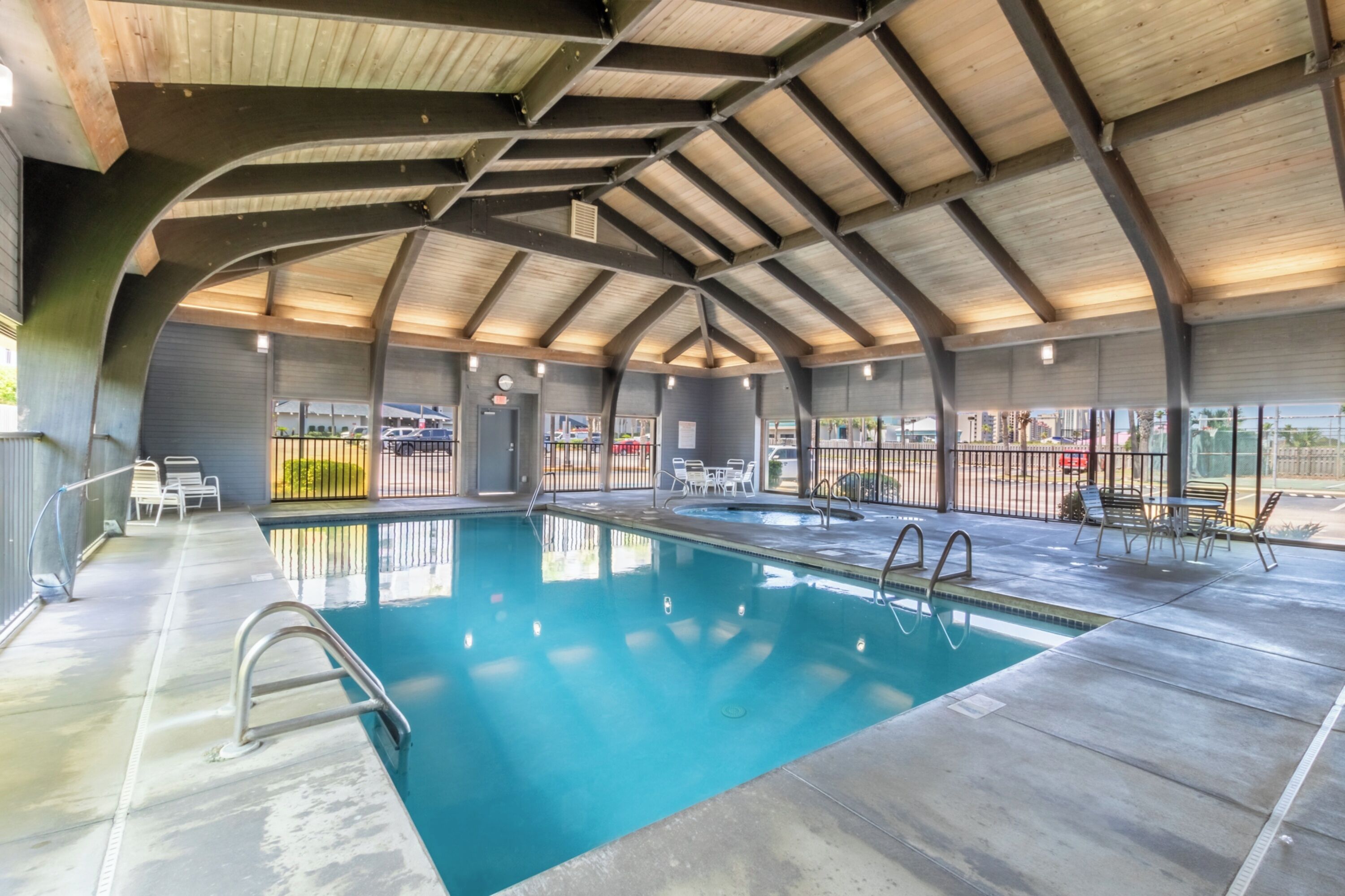 An indoor swimming pool with a high ceiling and a view of the city.