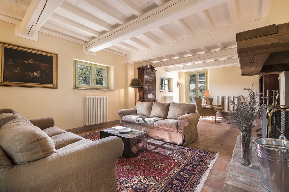 Un salon spacieux avec un plafond haut, une cheminée et un plafond en bois d’époque.