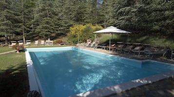 En sÀsongsöppen utomhuspool och solstolar