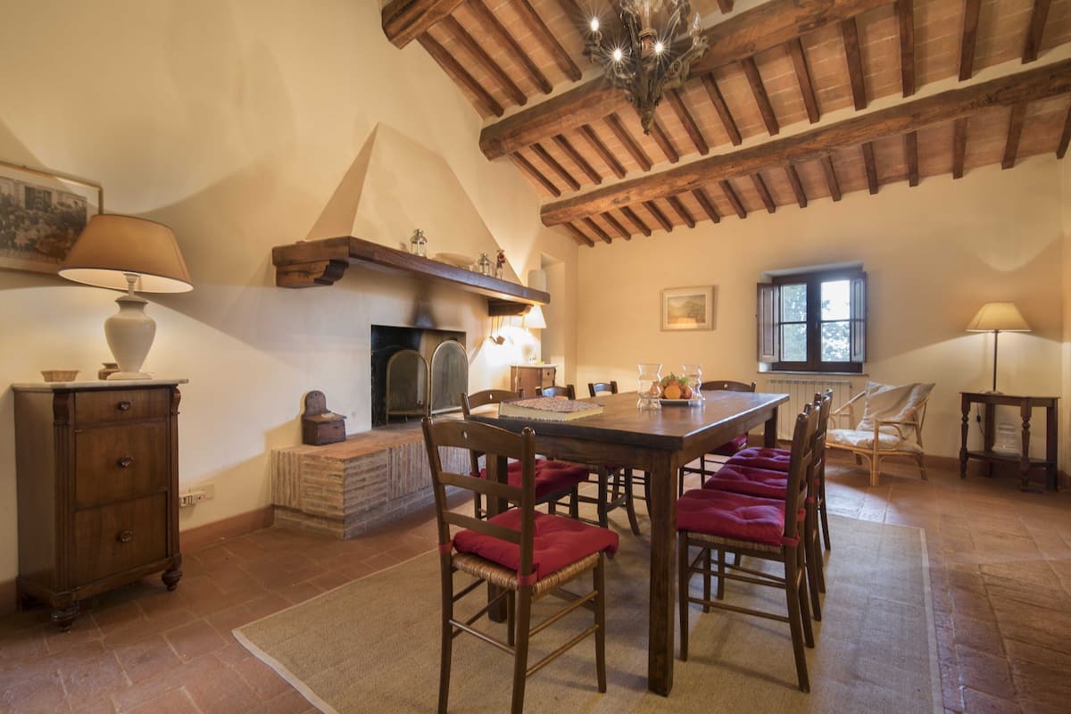 Un coin repas avec une table et des chaises en bois, une cheminée et un lustre.