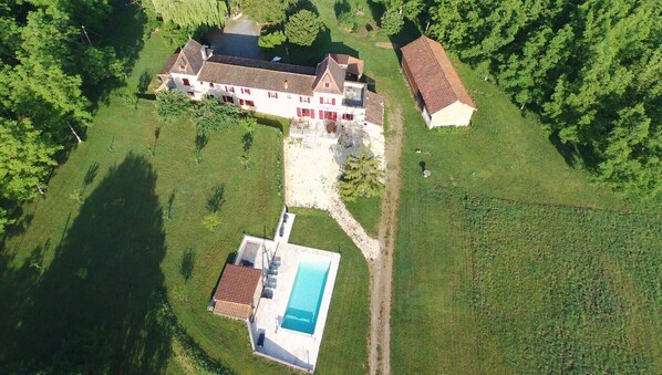 An aerial view of a property with a large house, a swimming pool, and a smaller building.