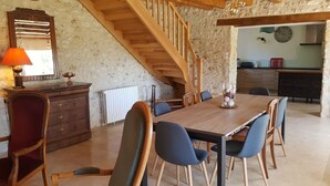 Een eethoek met een houten tafel en stoelen, een trap, een keuken op de achtergrond en een radiator.