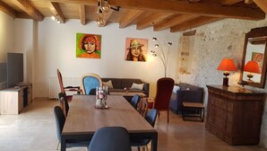 A dining area with a wooden table and chairs, a sofa, and a cabinet with a lamp. - La Truffière (Pays-de-Belvès)