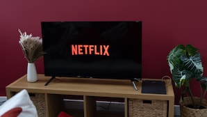 Ein Fernseher auf einem Holzständer vor einer roten Wand.