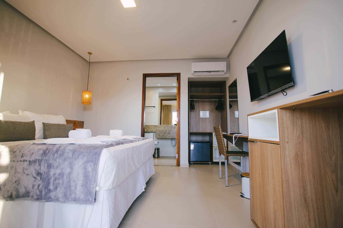 Une chambre d’hôtel moderne équipée d’un grand lit, d’une télévision, d’un bureau et d’un miroir.