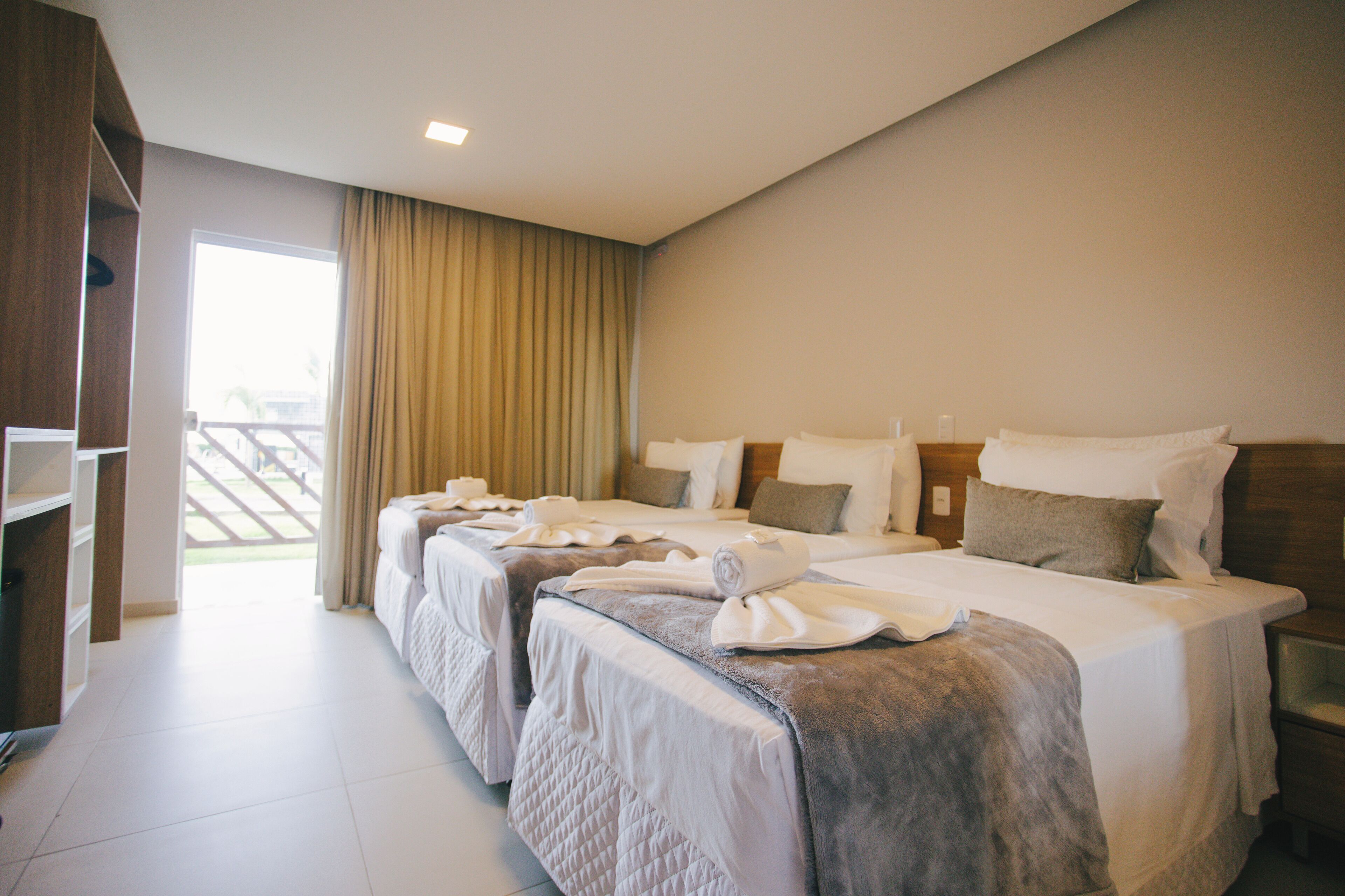 A hotel room with two beds, a large window, and a view of the outdoors.