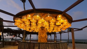 Een houten constructie met een rond zitgedeelte en hangende lampen.