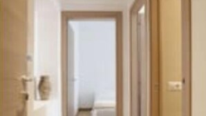 A hallway with wooden flooring leading to a bedroom with a bed and a nightstand. - DIMORA VATICAN apartment's Dx (Roma)