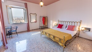 A bedroom with a bed, a window with a view, a chair, and a mirror. - Panoramic 3-bed Apartment in Catania City (Catania)