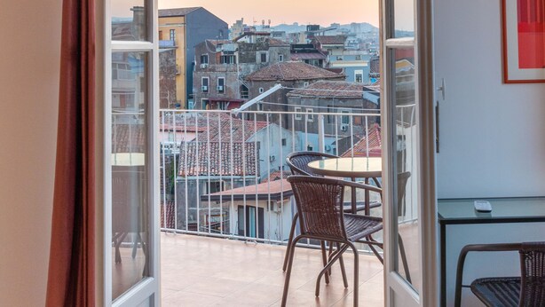 An open balcony with a view of buildings, a table, and chairs. - Panoramic 3-bed Apartment in Catania City (Catania)