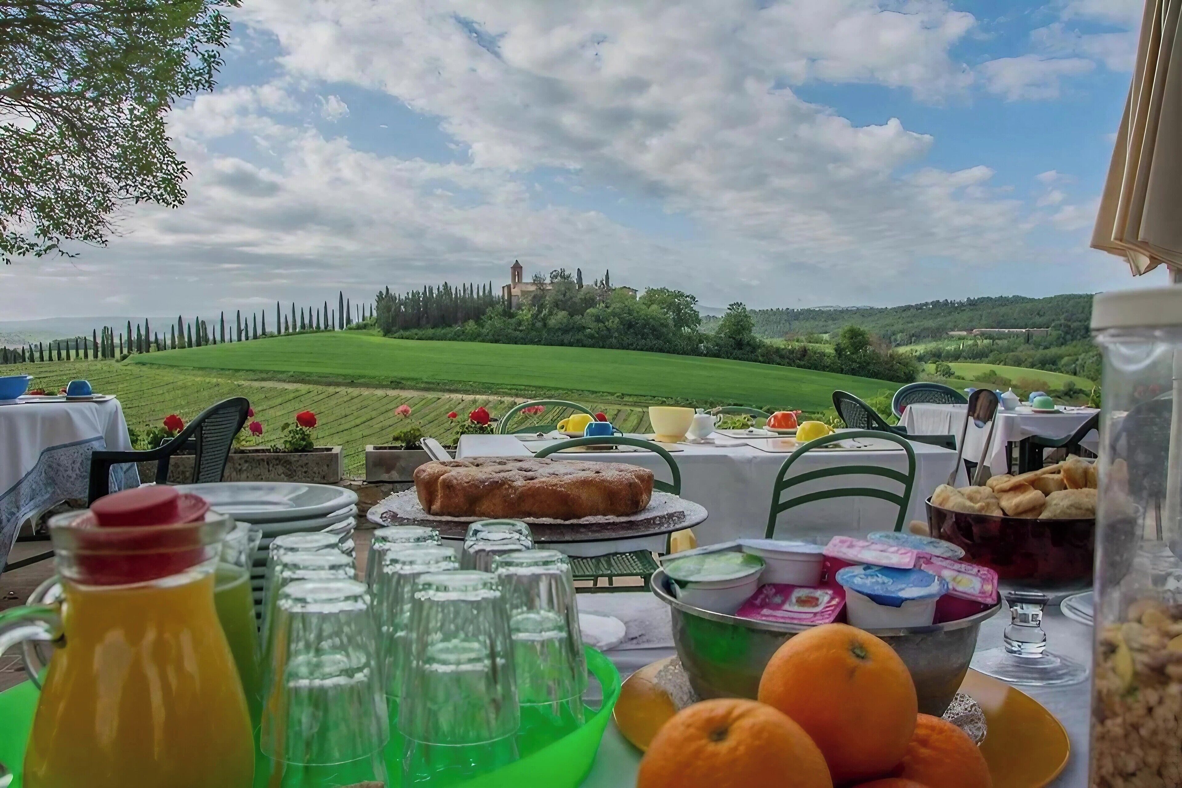 A table set for breakfast with a view of a green field and a distant building.