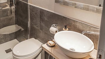 A modern bathroom with a glass-enclosed shower, a large mirror, and a white sink.