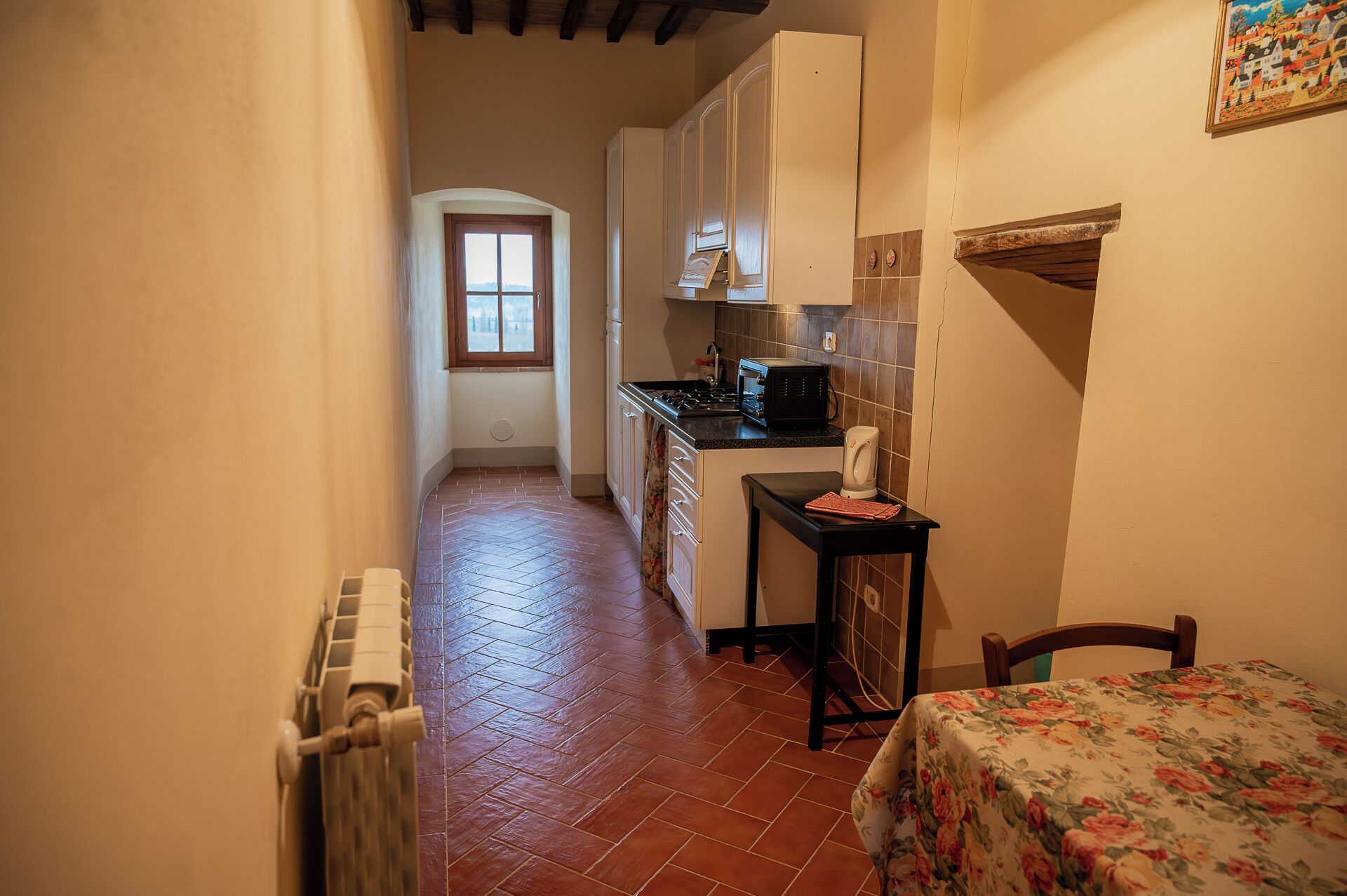 A narrow hallway leading to a kitchen with a stove, microwave, and cabinets.
