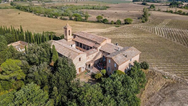 A large stone building with a bell tower, surrounded by fields and trees. - Agriturismo La Ripolina (Buonconvento)