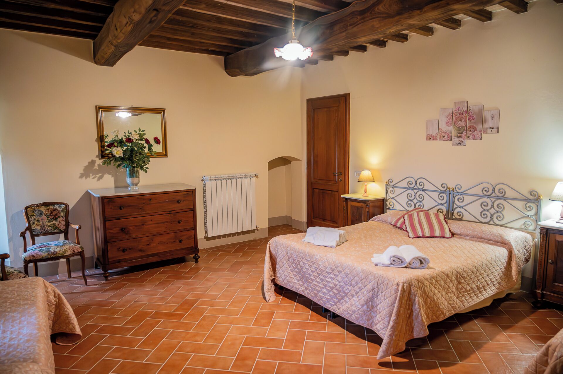 A bedroom with a bed, a dresser, a chair, a radiator, and a door.
