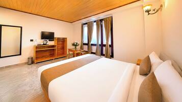 Een hotelkamer met een groot bed, houten meubels, een televisie en een raam met gordijnen.