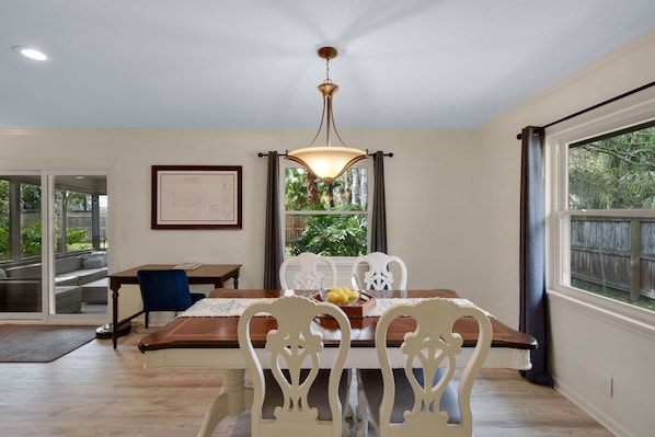 A dining area with a wooden table, white chairs, and a chandelier.