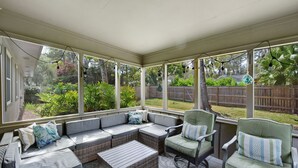 Un patio cubierto con un sofá modular, sillas y una pequeña mesa.