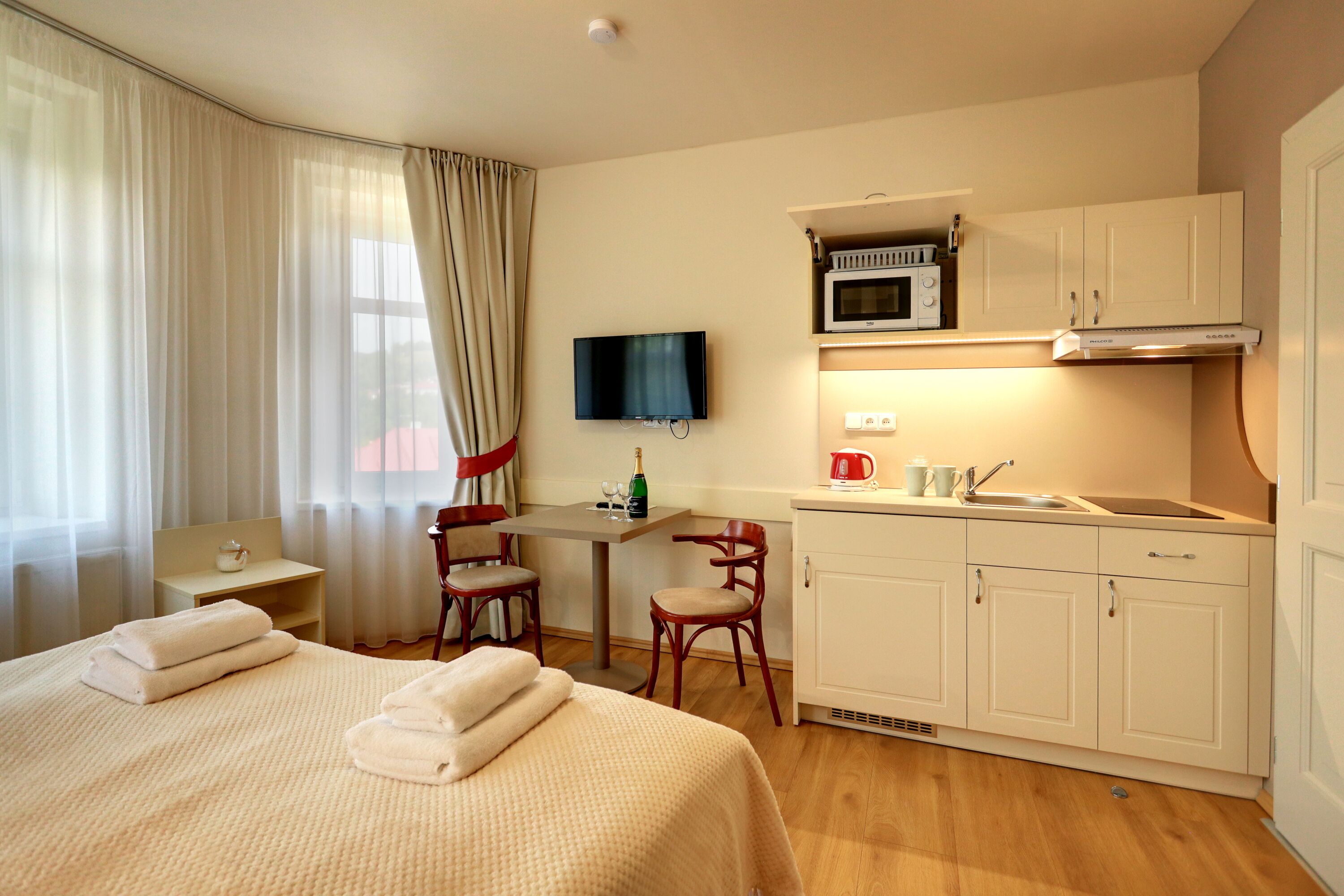 A hotel room with a bed, a desk, a microwave, and a sink.