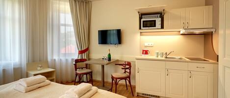 A hotel room with a bed, a desk, a microwave, and a sink.