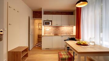 A modern kitchen with white cabinets, a brick backsplash, and a wooden dining table.