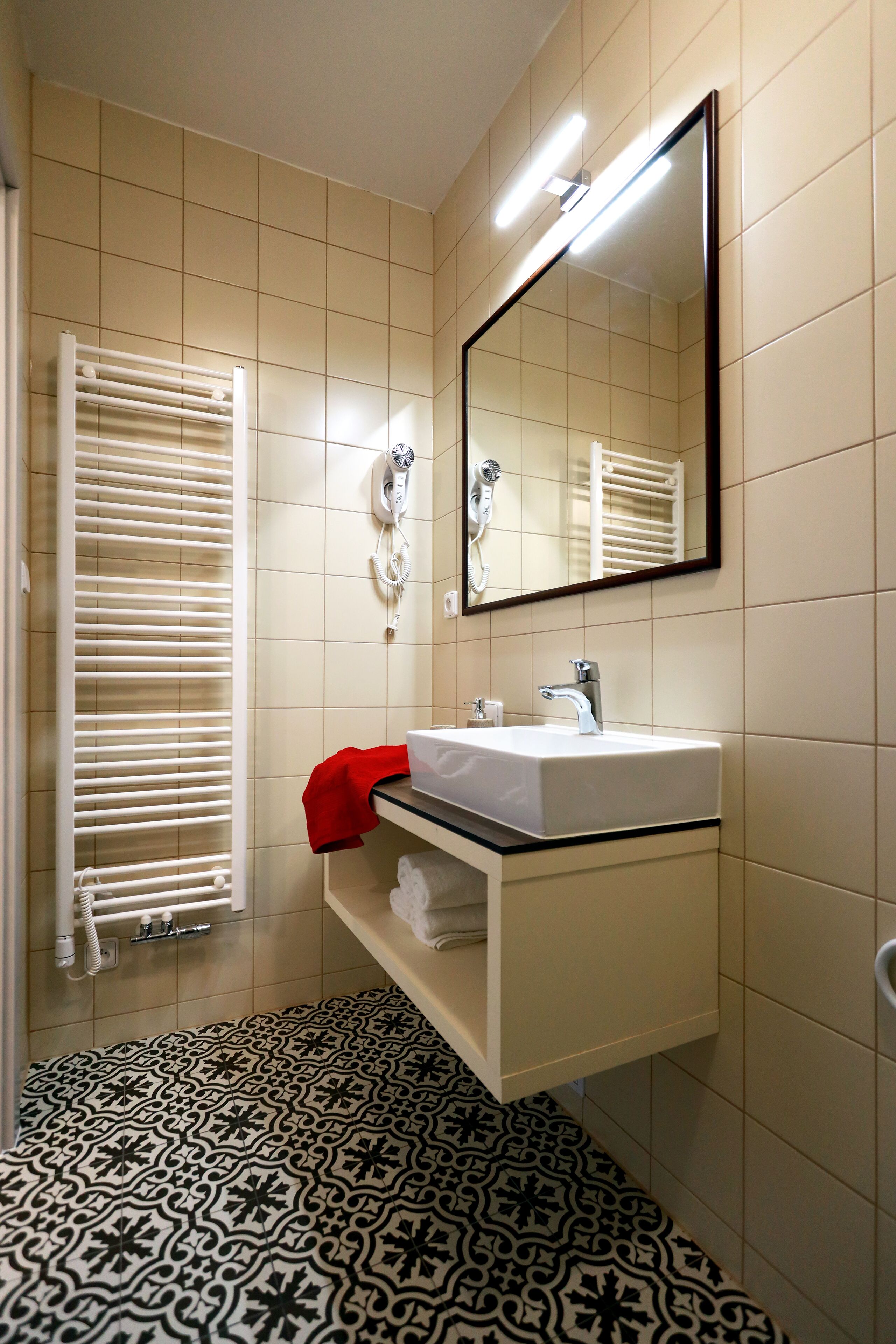 A bathroom with a white sink, mirror, and towel rack.