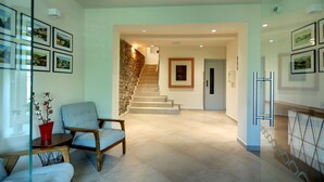 A spacious living area with a staircase, a red vase, and framed pictures on the walls. - Apartmány Adam (Jachymov)