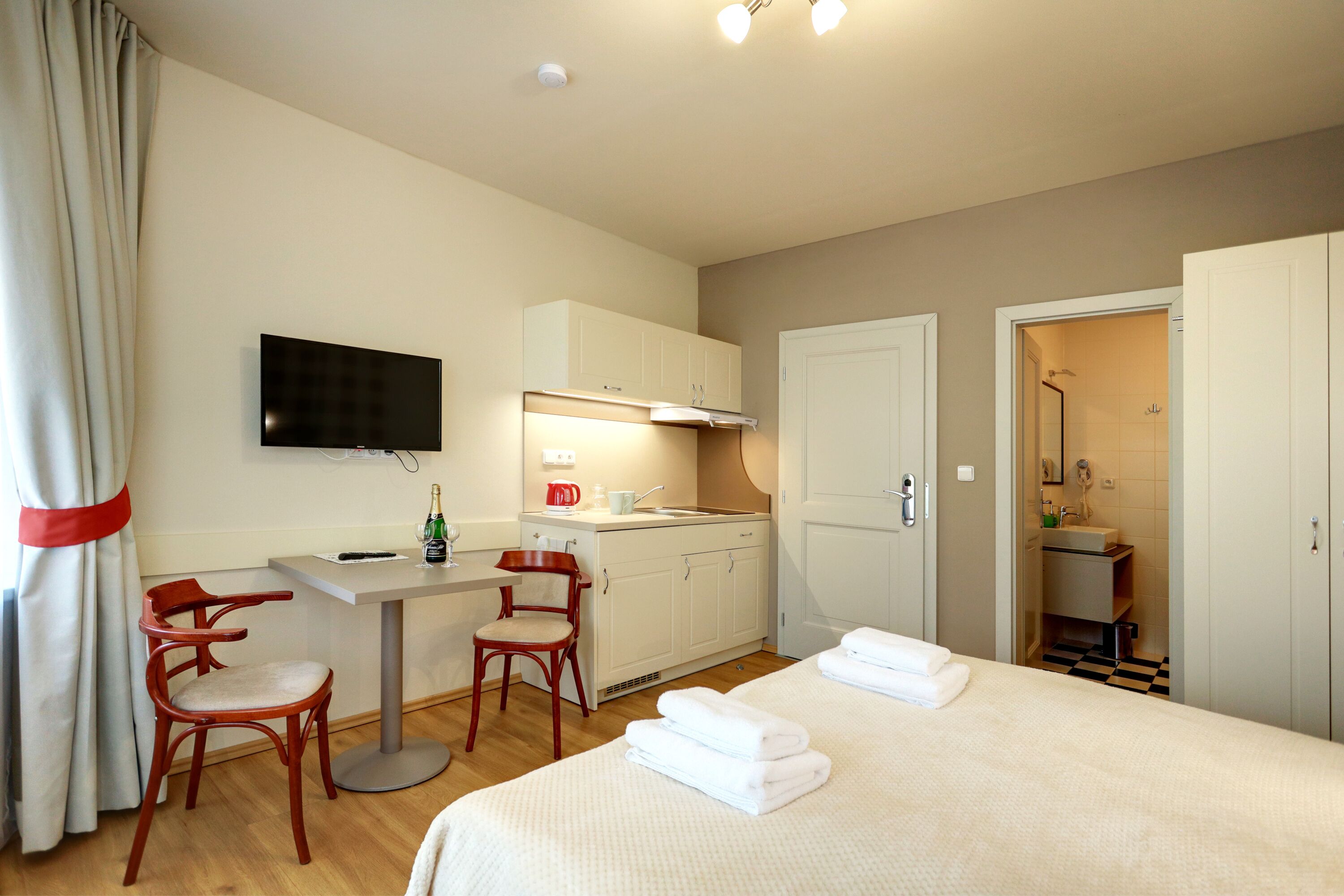 Une chambre d’hôtel comprenant un lit, un bureau avec une chaise, une télévision, une kitchenette et une salle de bain.