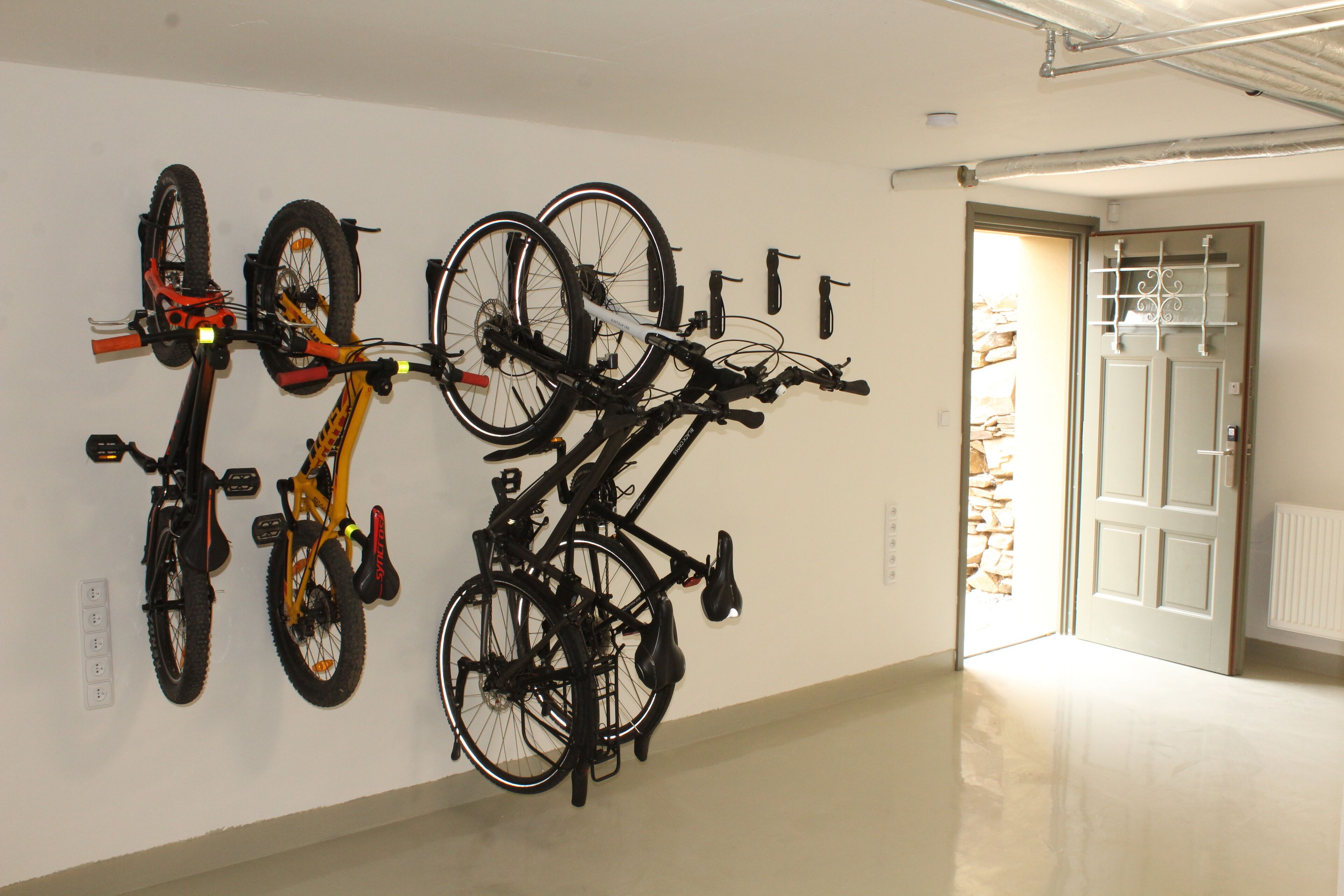 A hallway with bicycles mounted on the wall and a door leading to another room.