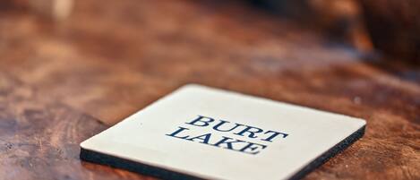 A square object with "BURT LAKE" text on it, placed on a wooden surface.
