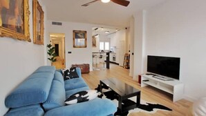 A modern living room with a blue sofa, a coffee table, a flat-screen TV, and a ceiling fan. - Modern & Style Mezquita (Córdoba)