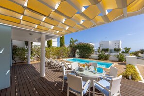Relax in a serene outdoor setting with a deck, lounge chairs, and a refreshing pool surrounded by lush greenery.