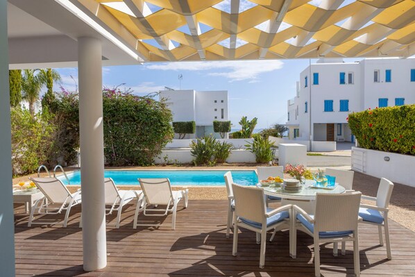 Relax by the pool surrounded by lush greenery and enjoy meals at the outdoor dining table.