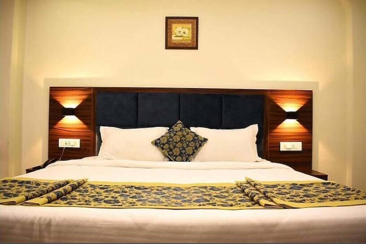 A neatly made bed with a patterned bedspread, a decorative pillow, and two wall-mounted lamps on either side.